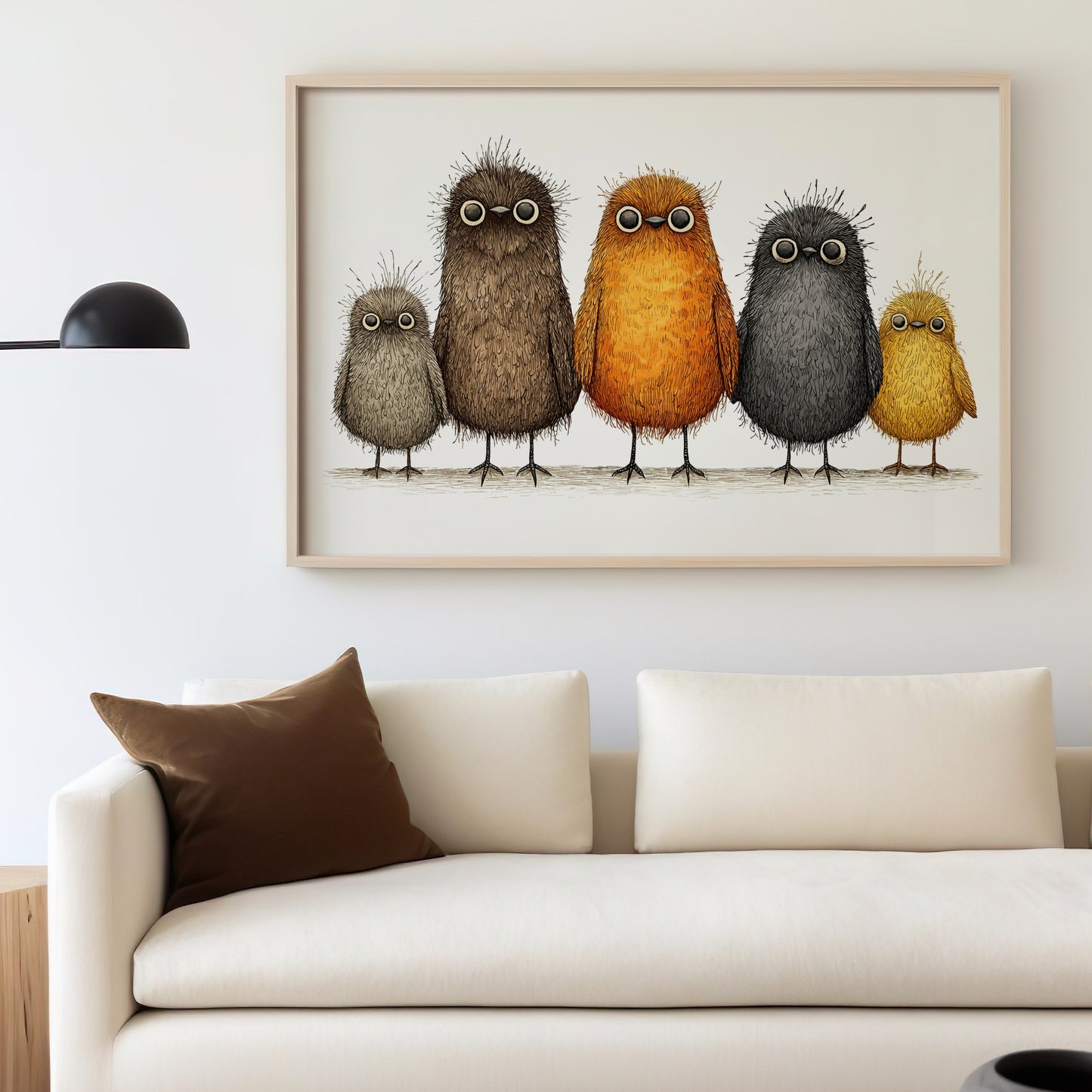 Framed artwork of five fuzzy, whimsical bird characters on a wall above a couch.