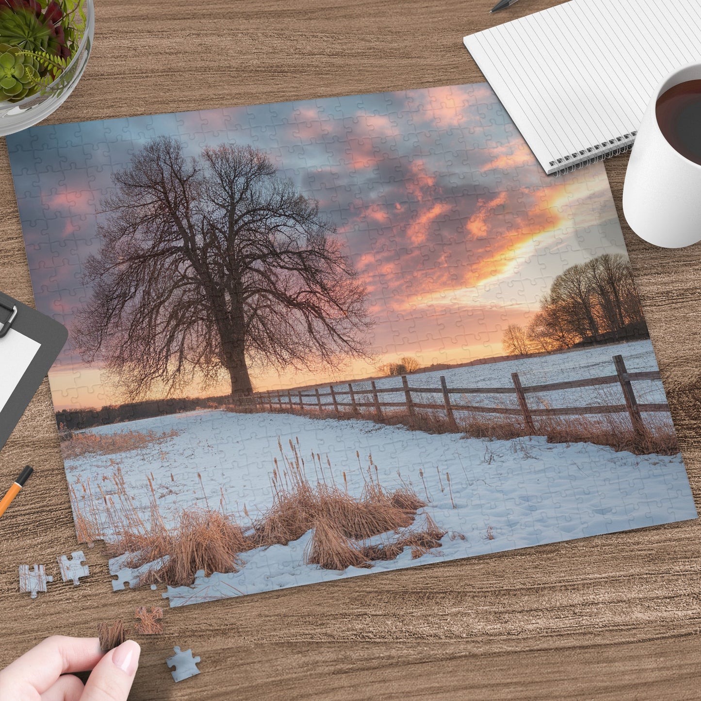 Winter landscape at sunset with large tree, fence, and a partial jigsaw puzzle.