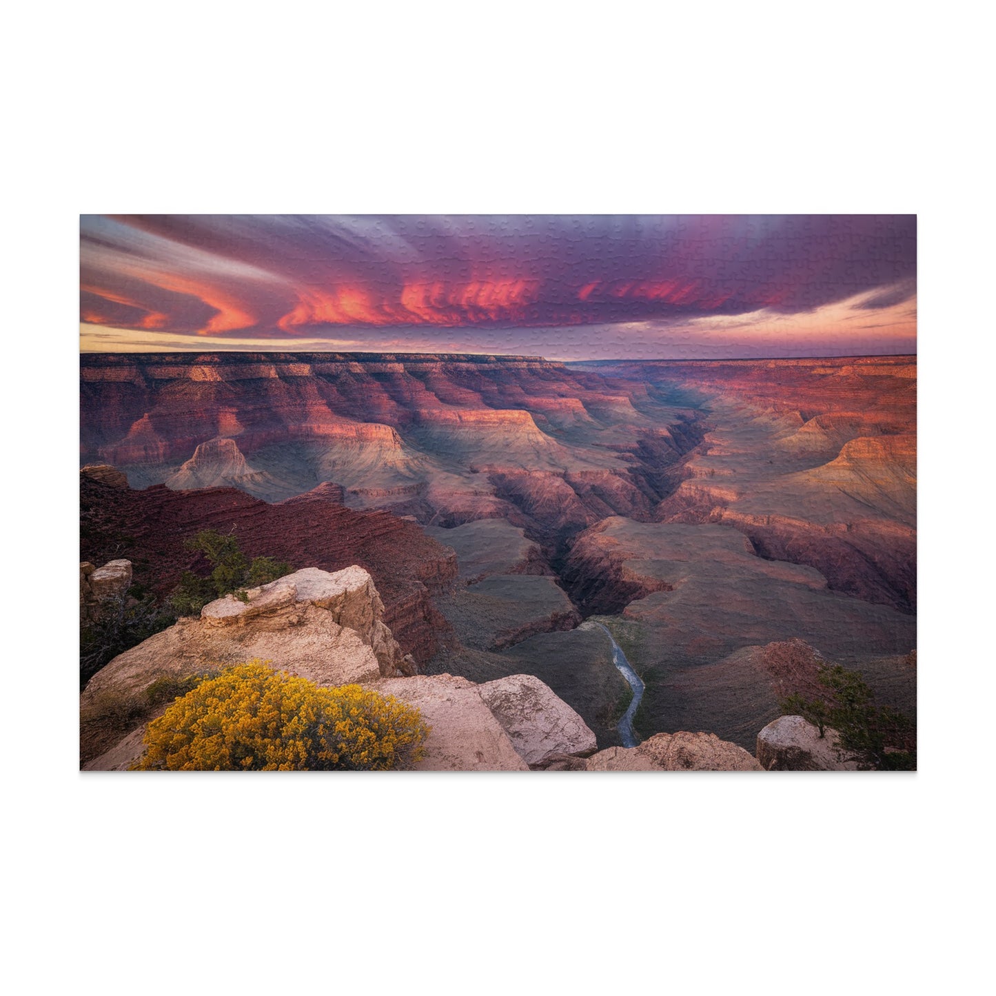 Grand Canyon at sunset with dramatic clouds and a winding river below.
