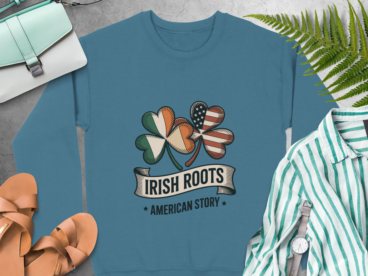 Shamrock design featuring Irish and American flags, text "IRISH ROOTS AMERICAN STORY" on Indigo Blue sweatshirt