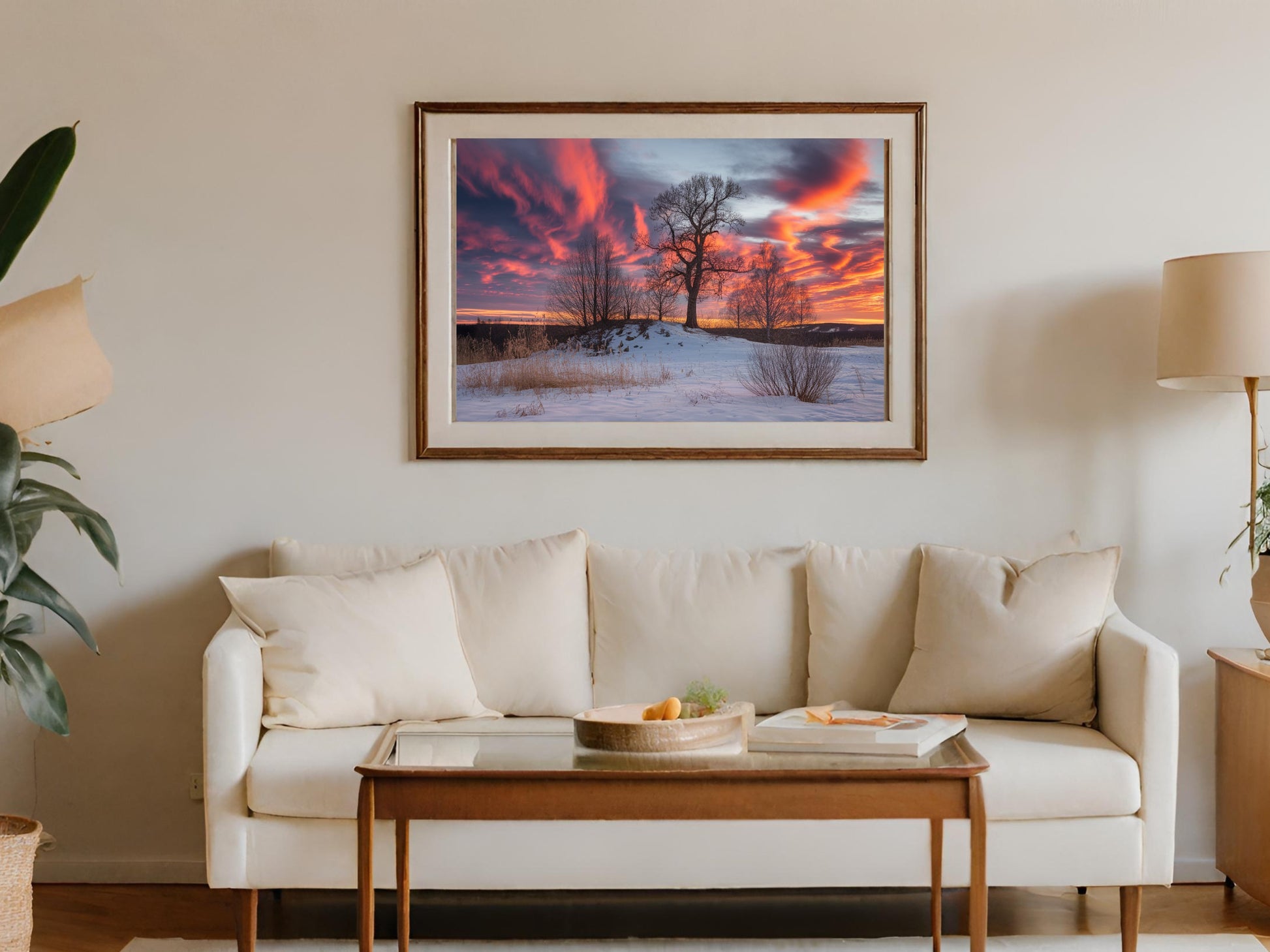 Framed sunset landscape art hangs above a cream sofa with a wooden coffee table.