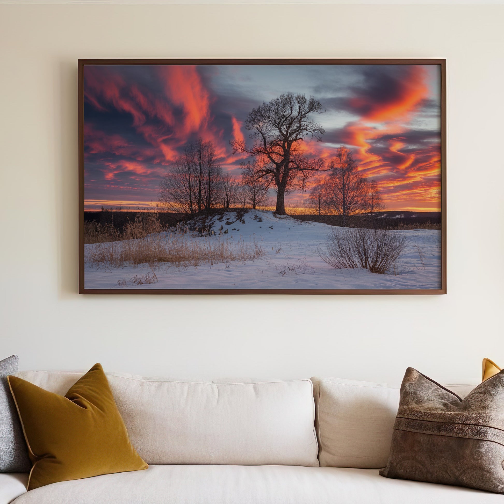 Framed artwork depicting a tree on a snowy hill at sunset.