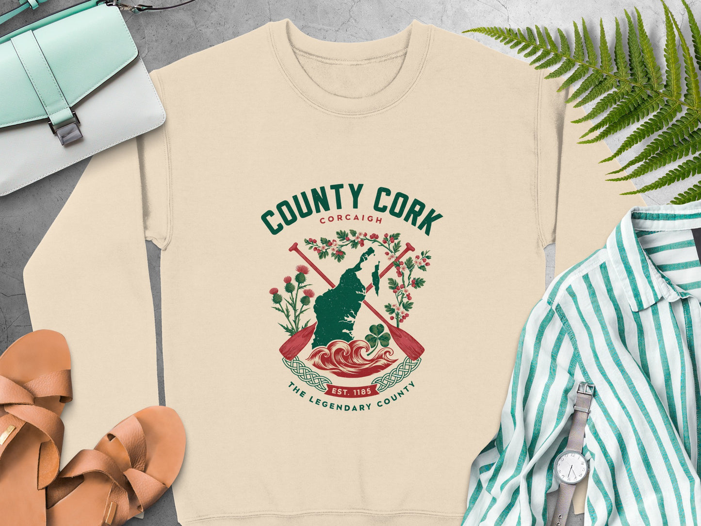 "County Cork" graphic featuring map, paddles, flowers, and "Est. 1185" text on Sand sweatshirt