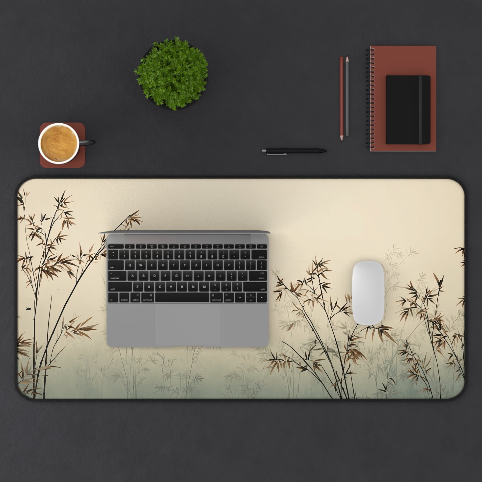 Desk setup with a large desk mat featuring bamboo design, laptop, mouse, and office supplies on a dark surface.