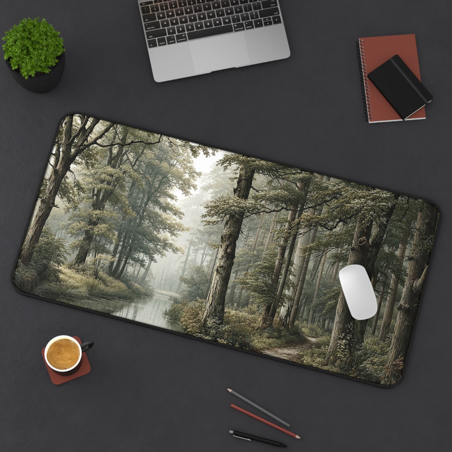 Desk setup with a forest-themed mouse pad, laptop, phone, and coffee cup on a dark surface.