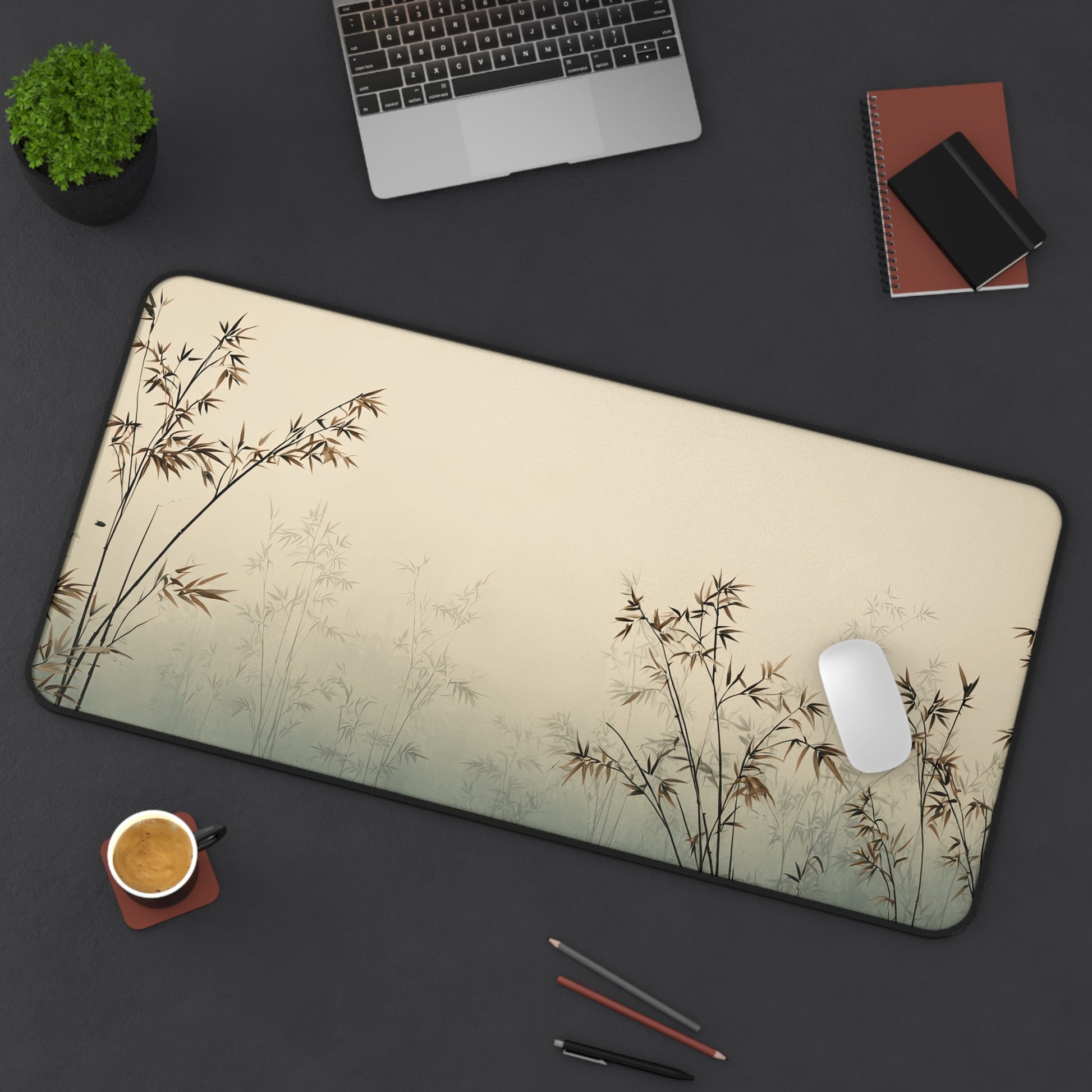 Desk setup with a large mouse pad featuring bamboo design, laptop, phone, and office supplies on a dark surface.