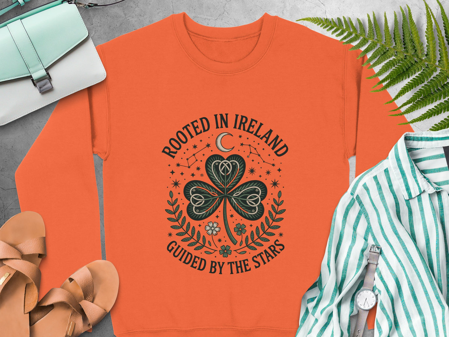 Orange sweatshirt with "Rooted in Ireland Guided by the Stars" text and shamrock design.