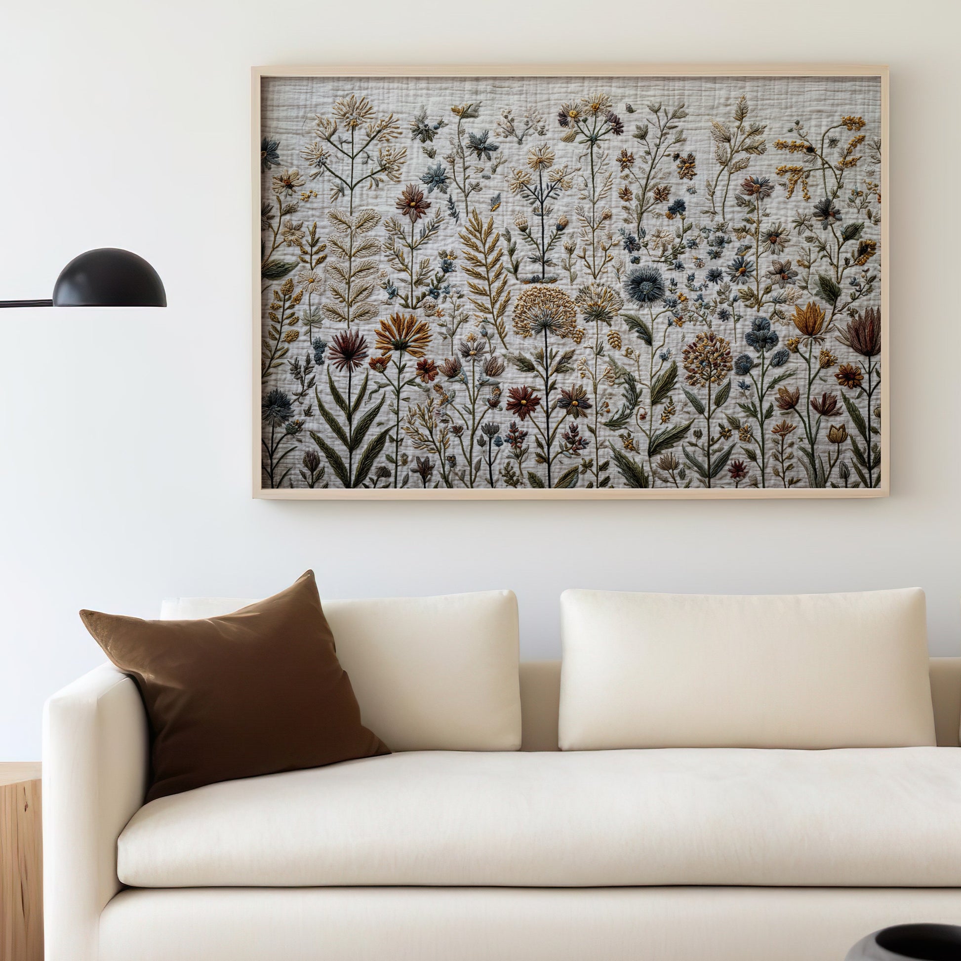 Framed botanical art above a cream sofa with a brown pillow.
