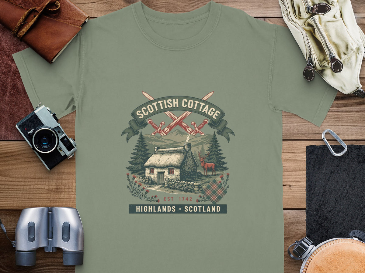 T-shirt graphic: Scottish cottage, crossed swords, deer, and tartan pattern.