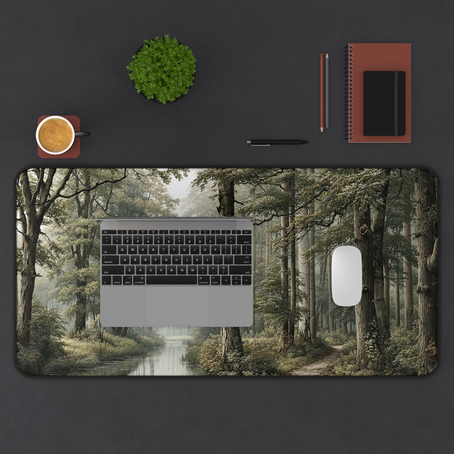Desk setup with a laptop on a forest-themed desk pad, surrounded by office supplies.