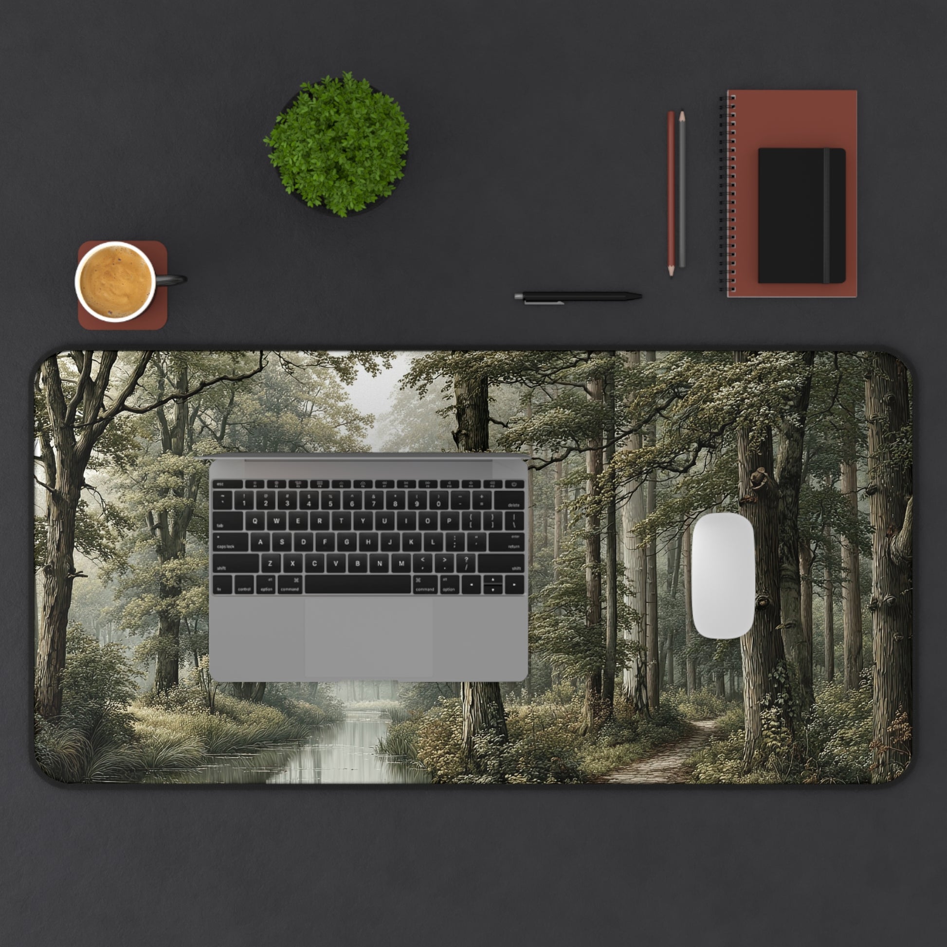 Desk setup with a laptop on a forest-themed desk pad, surrounded by office supplies.