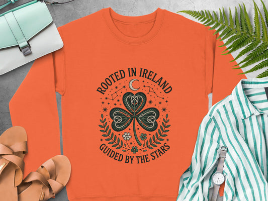 Orange sweatshirt with shamrock and text "Rooted in Ireland Guided by the Stars."