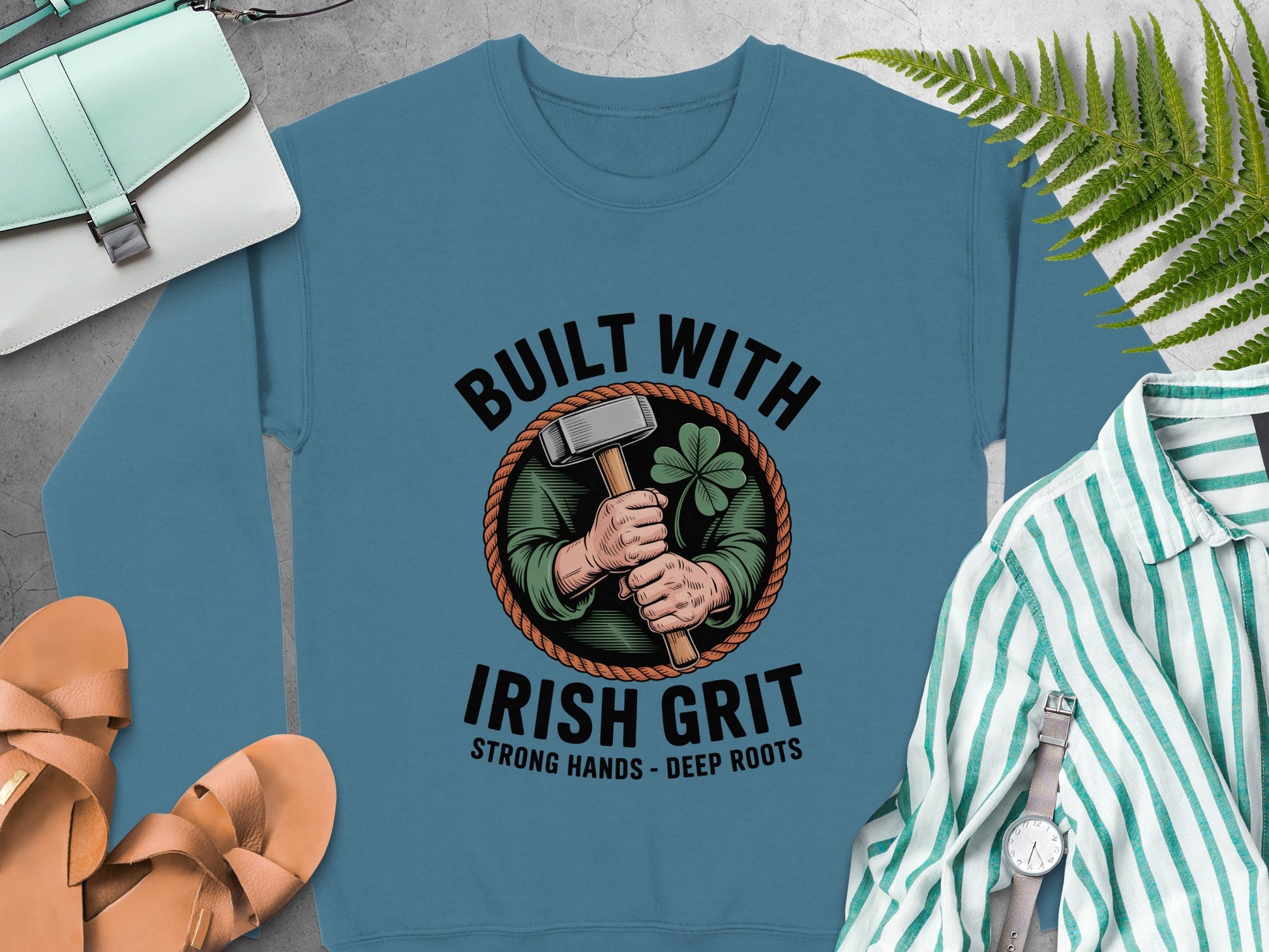 "Built With Irish Grit" graphic of hands holding a hammer and shamrock on Indigo Blue sweatshirt