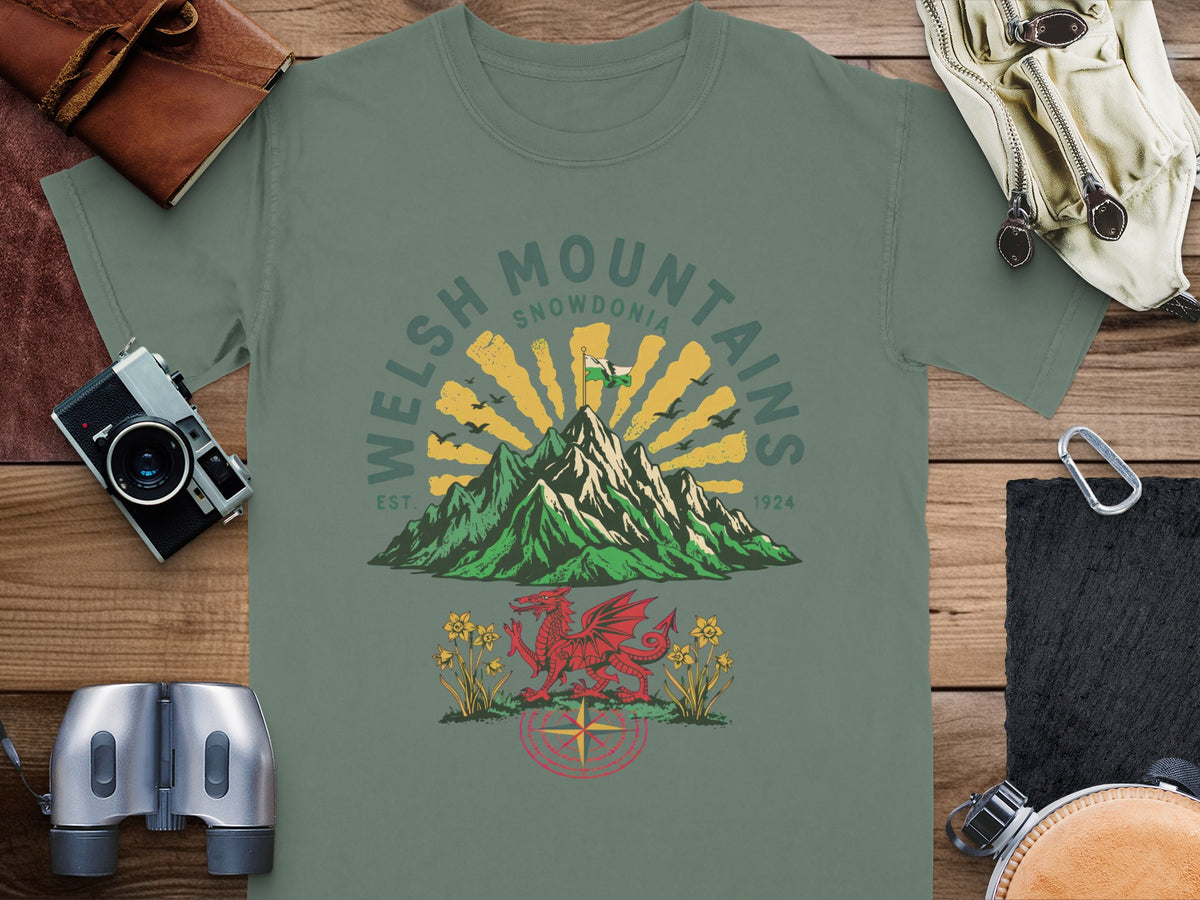 Green t-shirt graphic of Welsh mountains, a dragon, daffodils, and a compass.