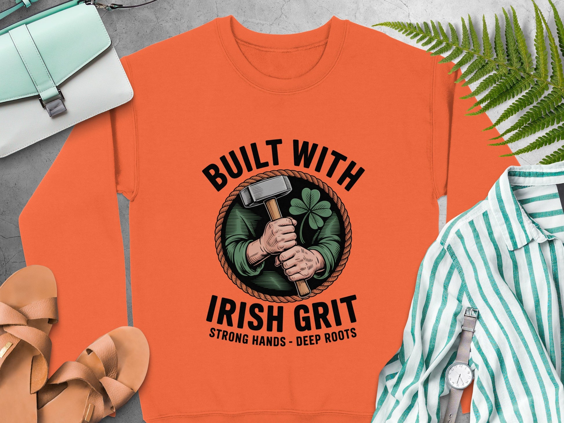 Orange sweatshirt with "Built With Irish Grit" graphic and clover emblem.