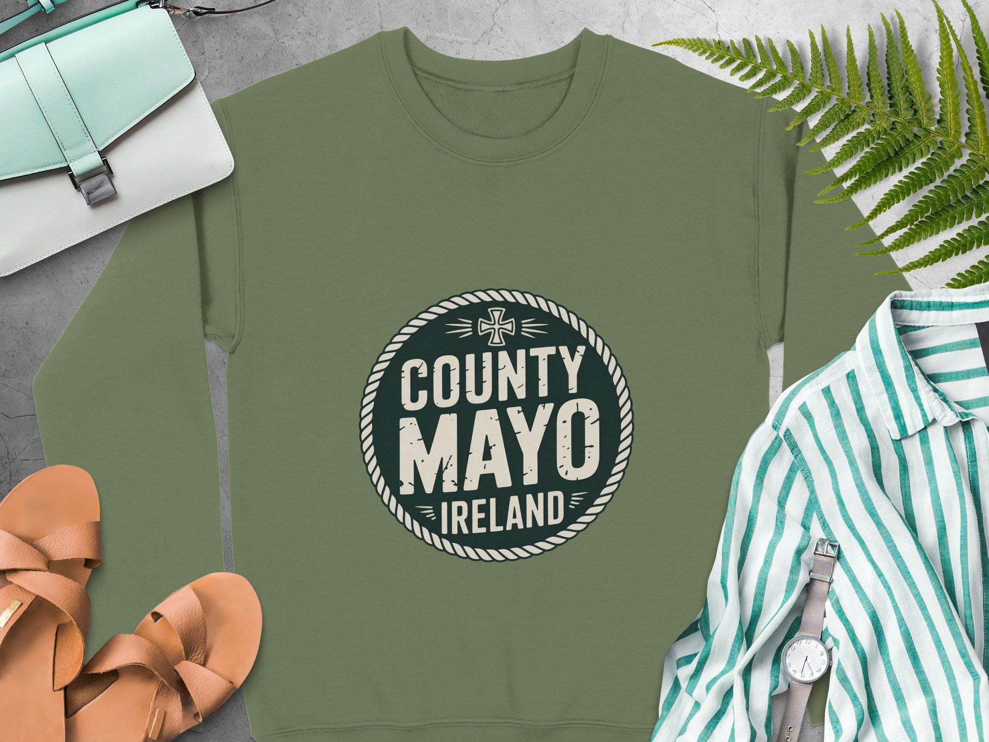 "County Mayo Ireland" graphic, surrounded by accessories on Military Green sweatshirt