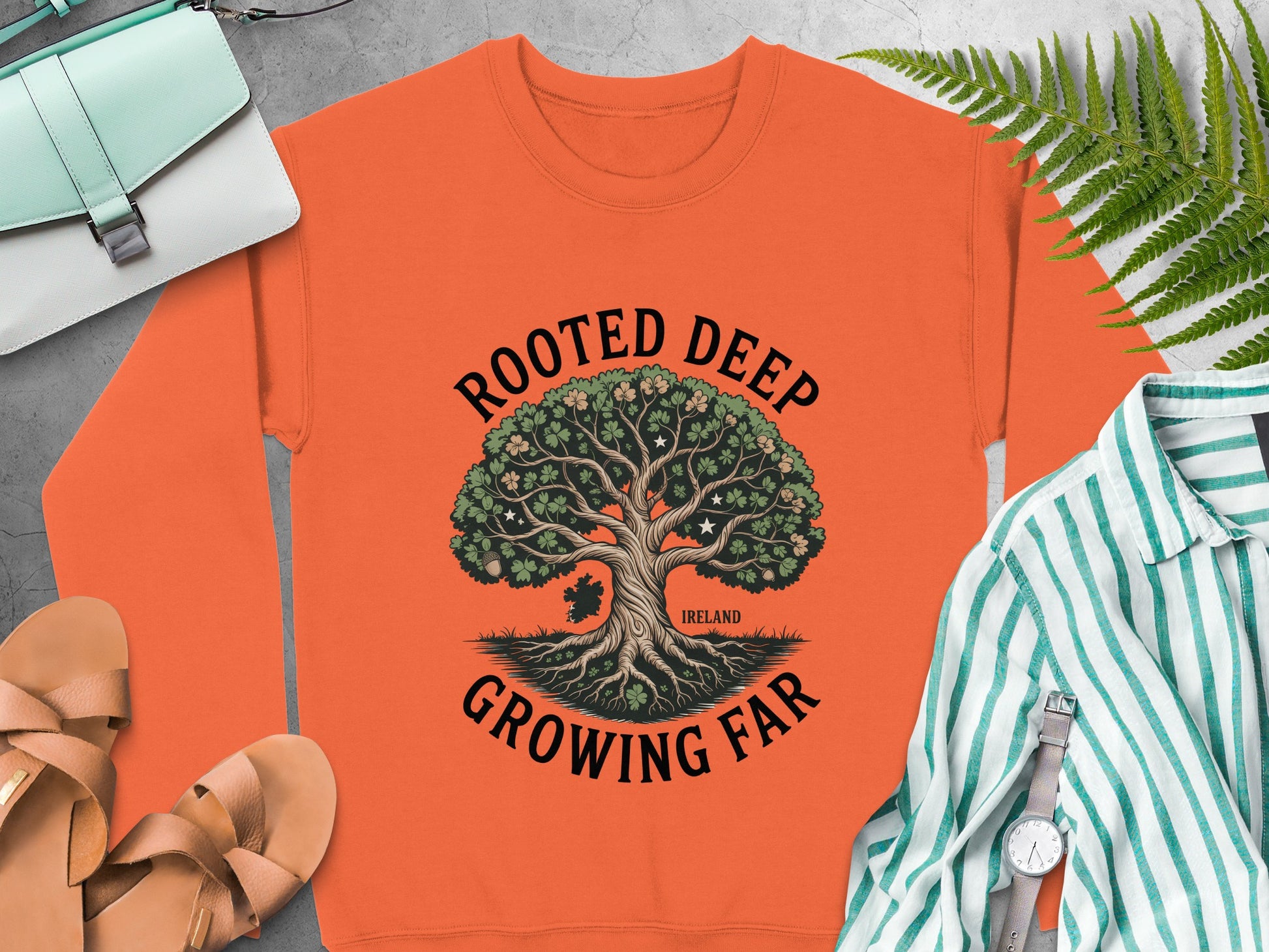 Orange sweatshirt with a tree graphic and text "Rooted Deep Growing Far Ireland".
