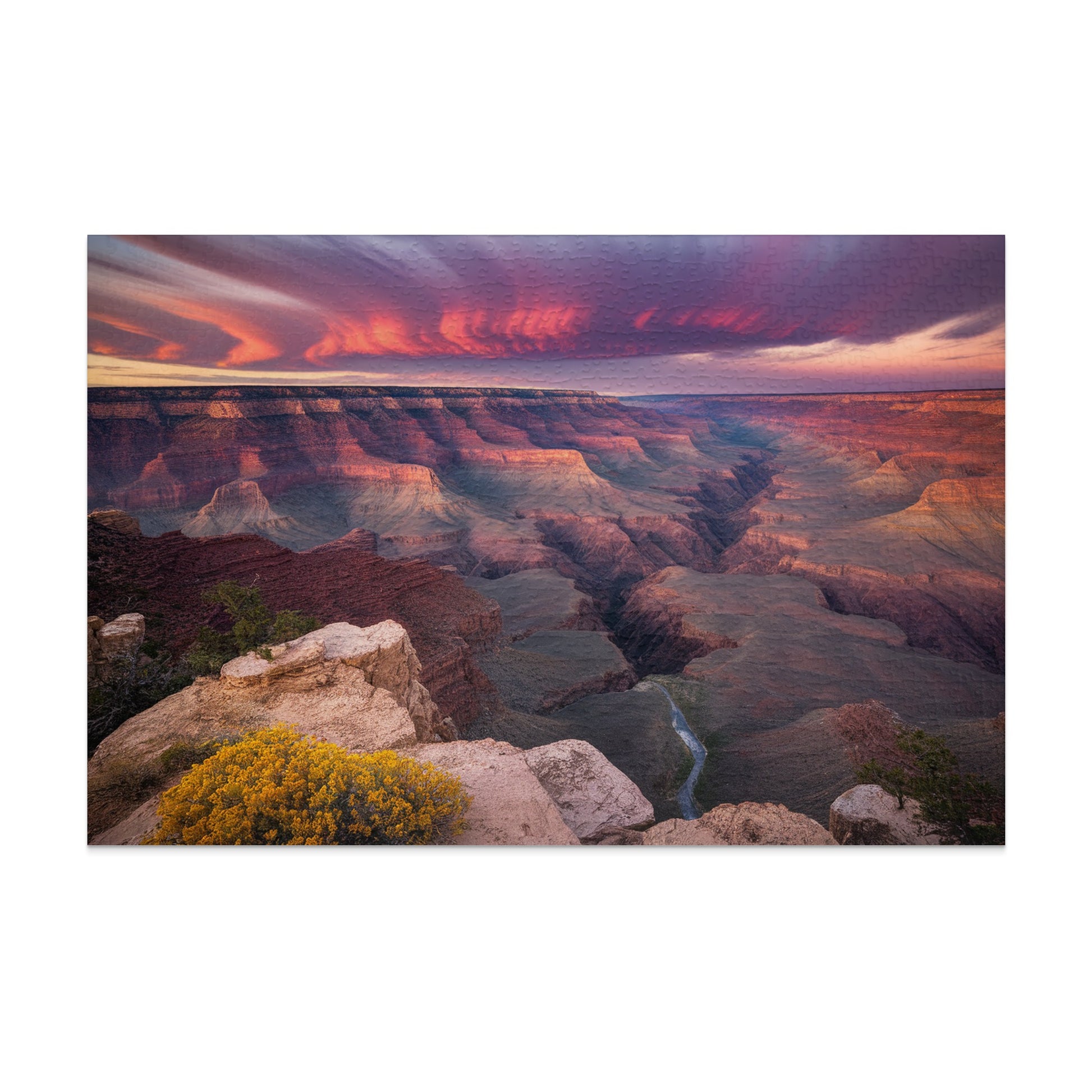 Grand Canyon at sunset with dramatic clouds and a winding river below.