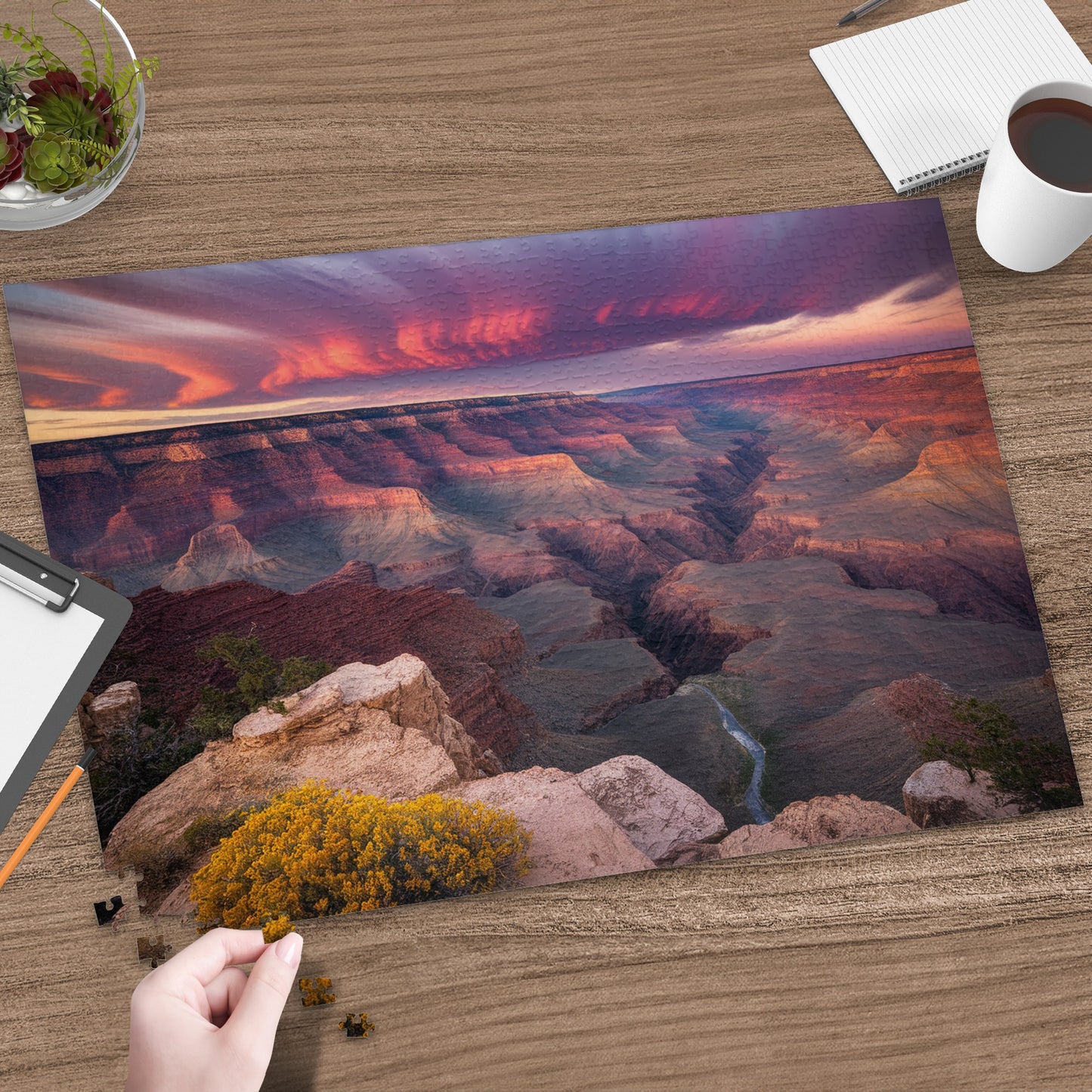 Grand Canyon at sunset with a hand placing a puzzle piece.