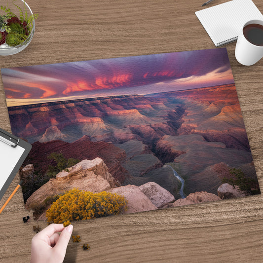 Grand Canyon at sunset with a hand placing a puzzle piece.
