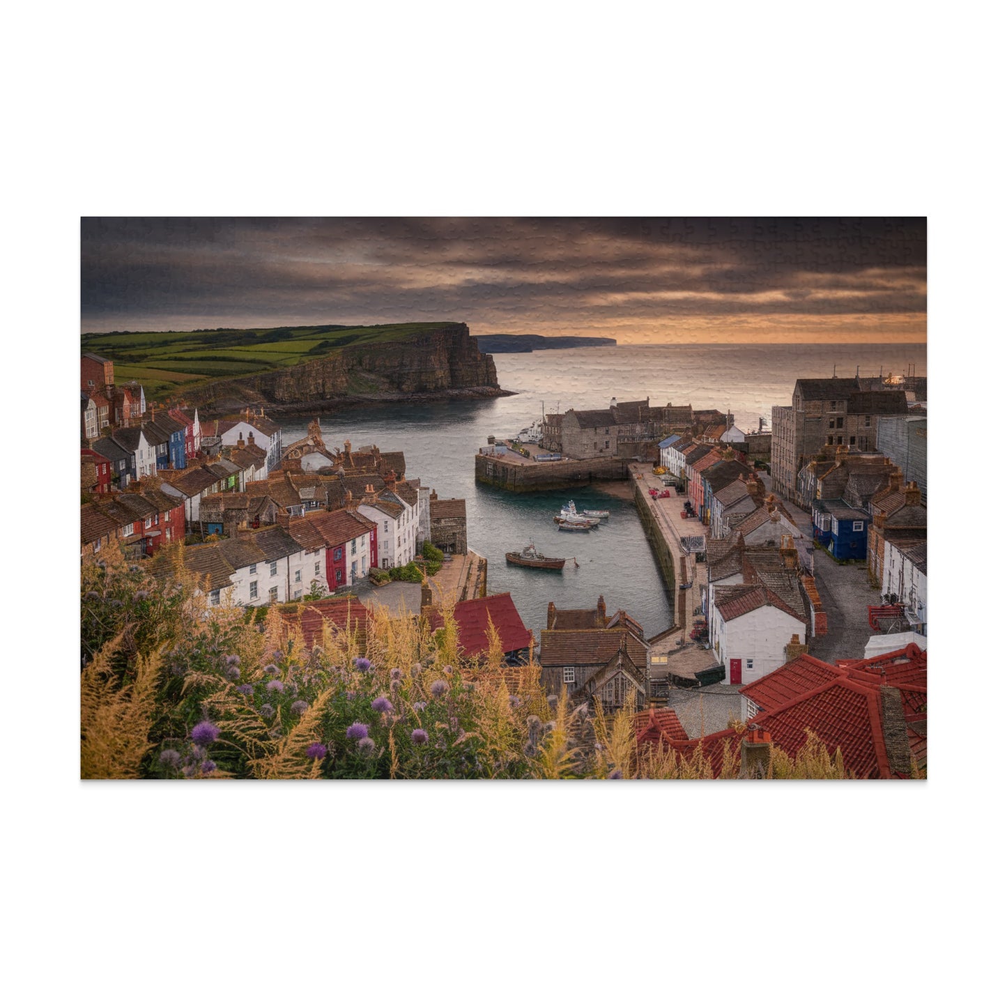 Coastal village harbor with colorful buildings, boats, and cliffs under a dramatic sky.