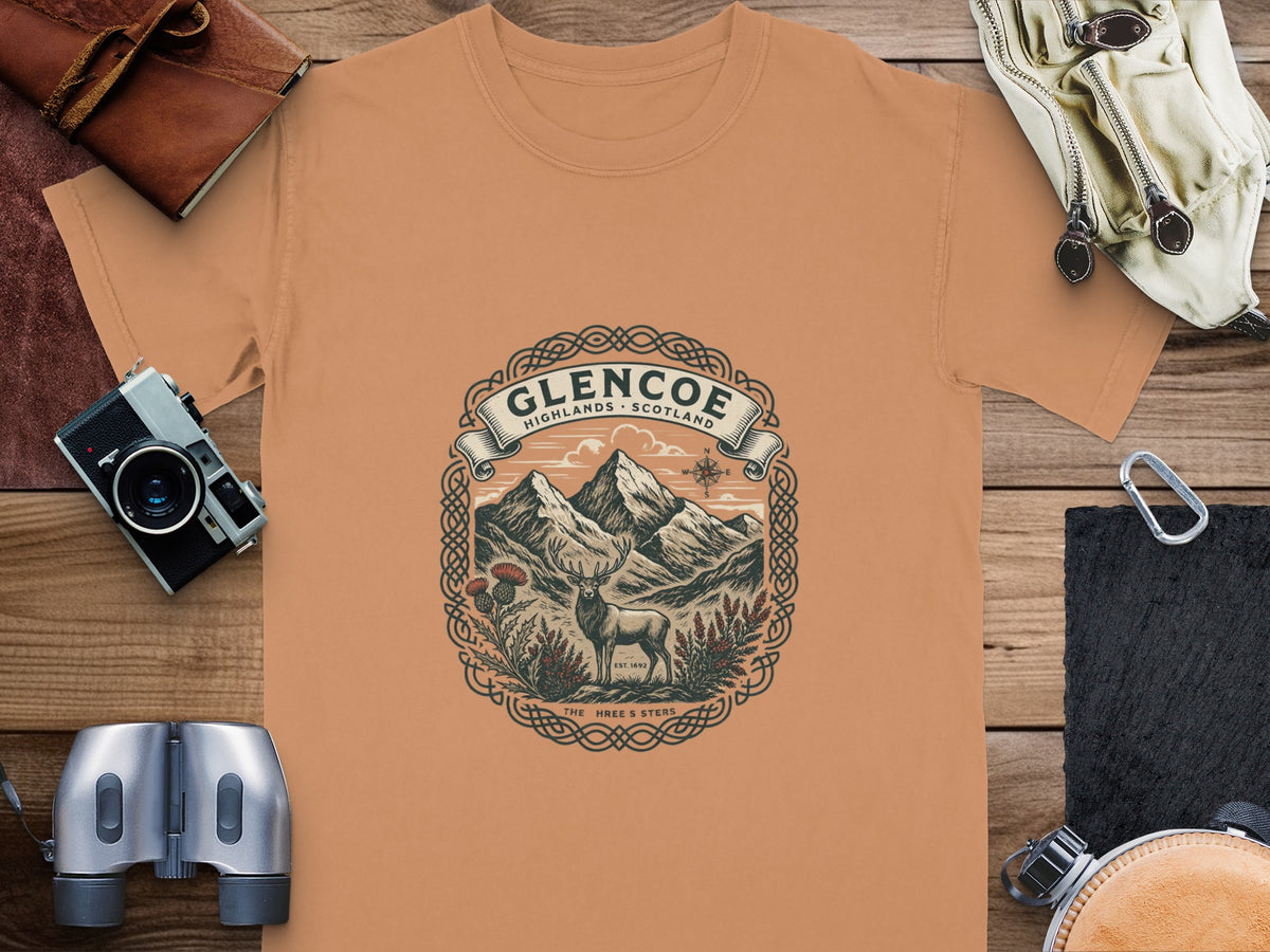 Glencoe Highlands Scotland graphic on orange t-shirt with mountains, deer, and thistle.