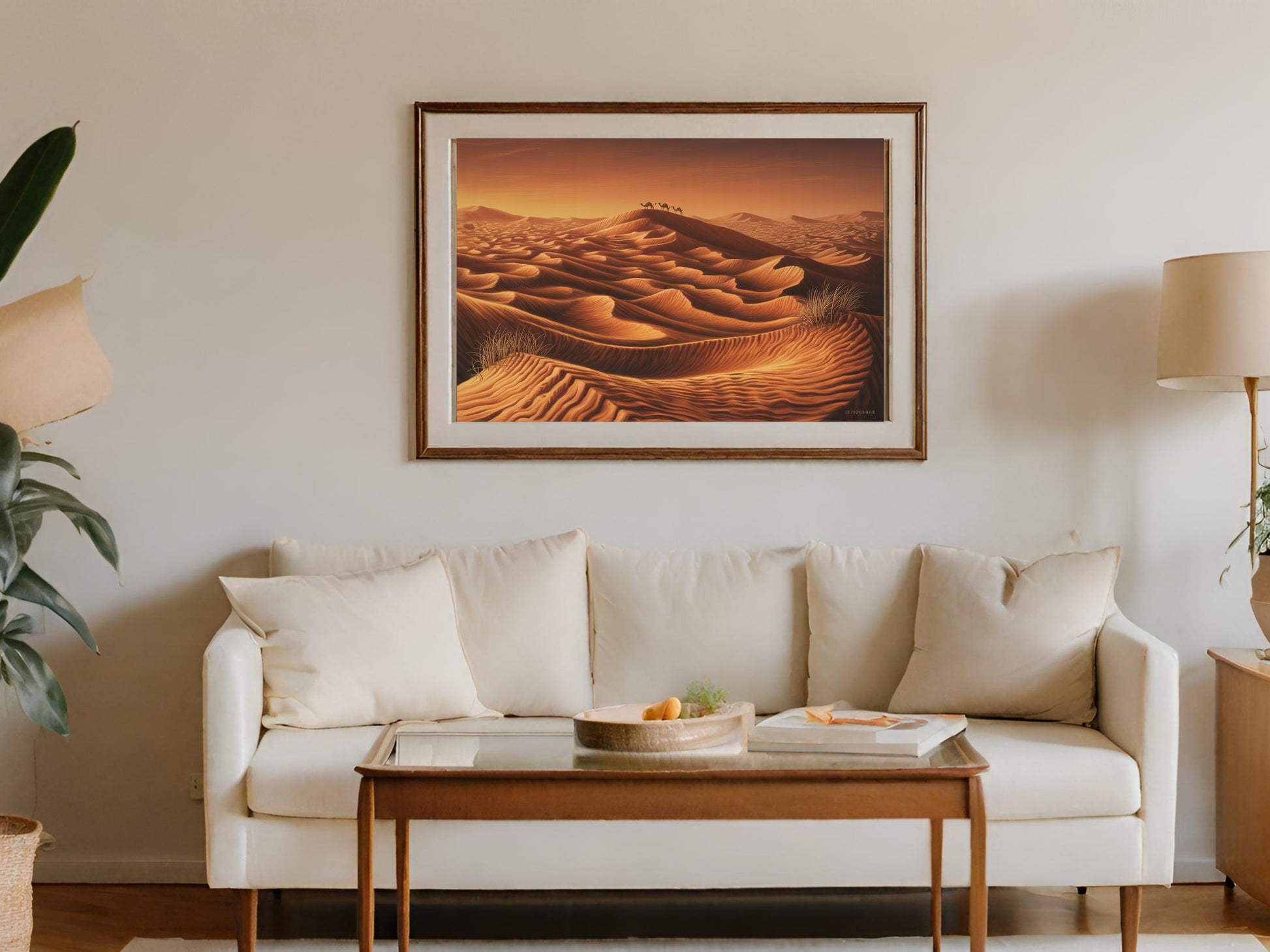 Framed desert landscape painting showing camels on sand dunes at sunset.
