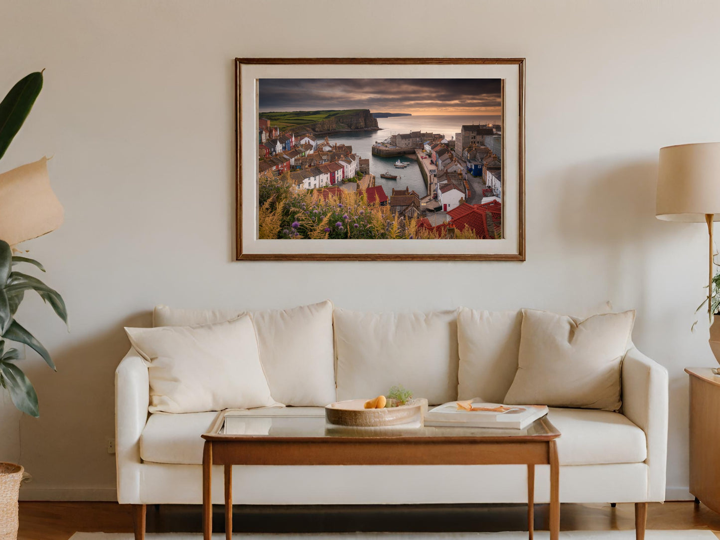 Framed artwork of a coastal village harbor at sunset with boats.