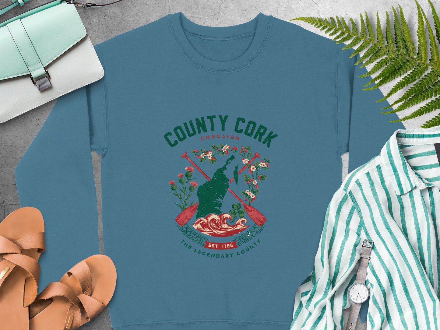 "County Cork" crest featuring a map outline, oars, flowers, and waves on Indigo Blue sweatshirt