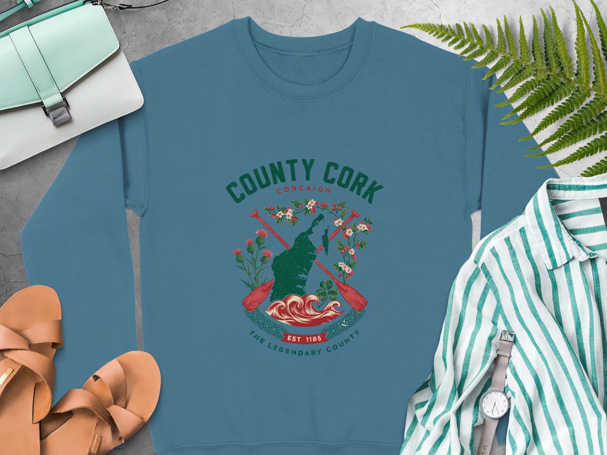 "County Cork" crest featuring a map outline, oars, flowers, and waves on Indigo Blue sweatshirt