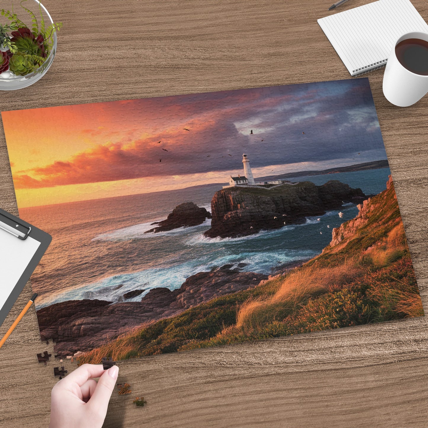 Lighthouse on rocky island at sunset with crashing waves and birds flying.