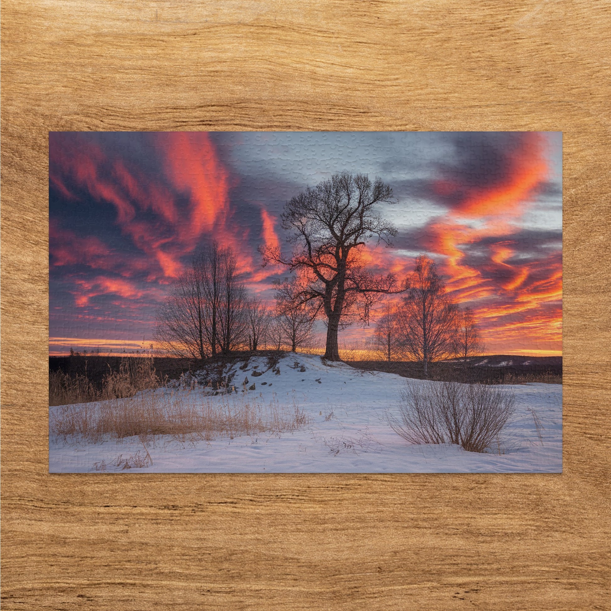 Snowy landscape with a large tree under a dramatic red and orange sky.